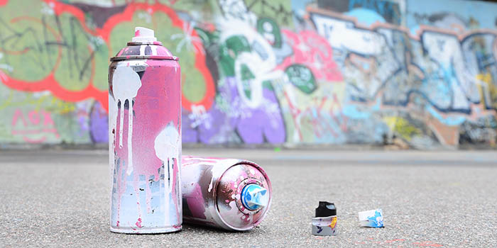 Several used spray cans with pink and white paint and caps 